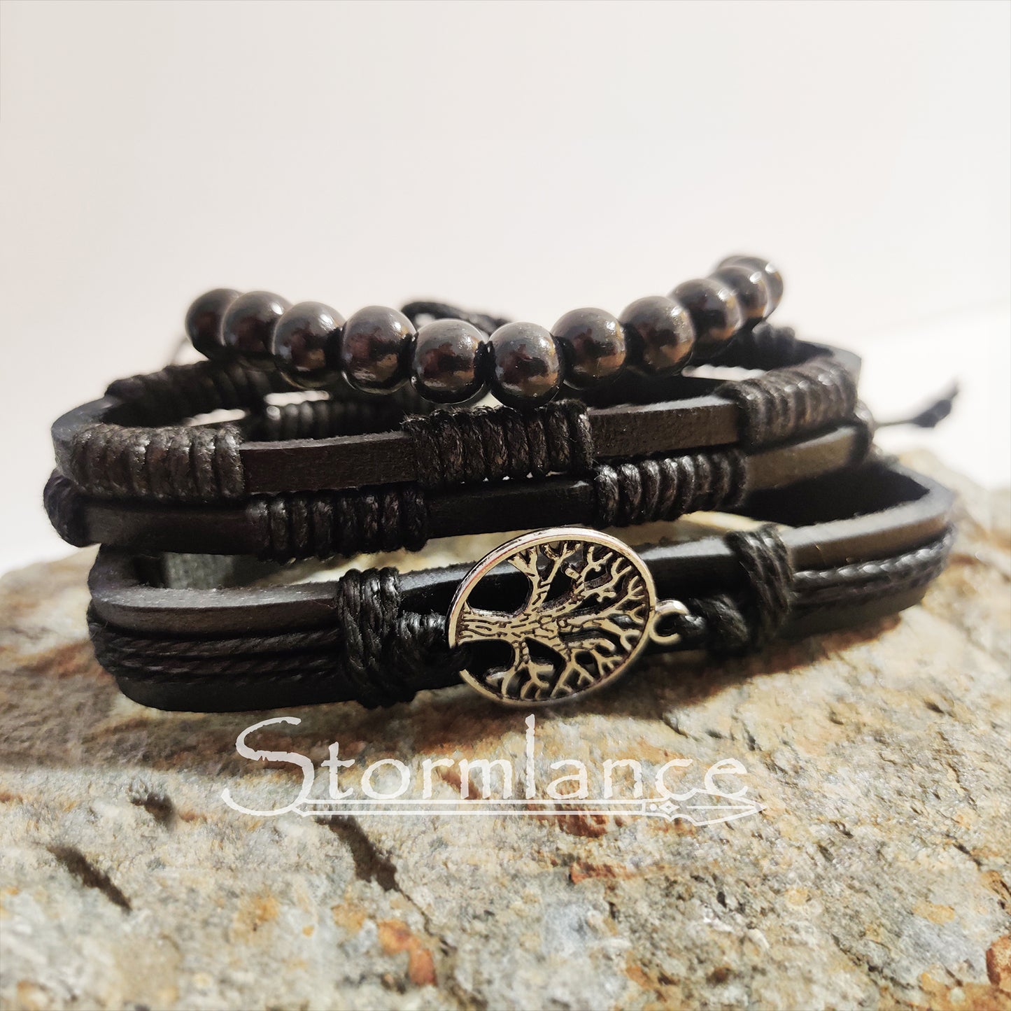 black PU leather bracelet with yggdrasil laying on a granite stone slab