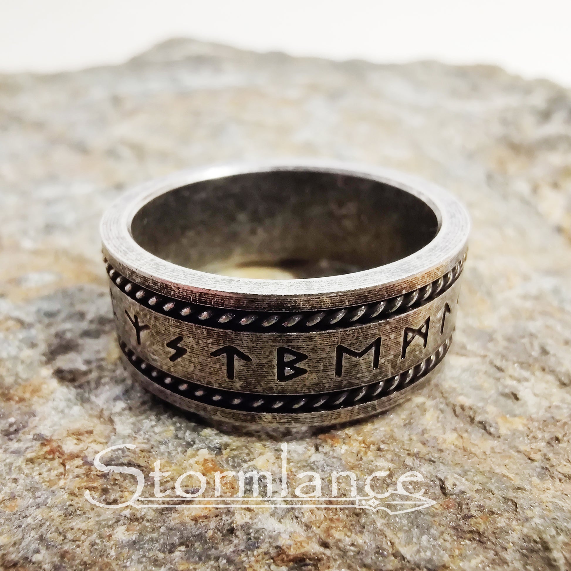 elder futhark rune ring made of stainless steel, laying on a granite stone slab