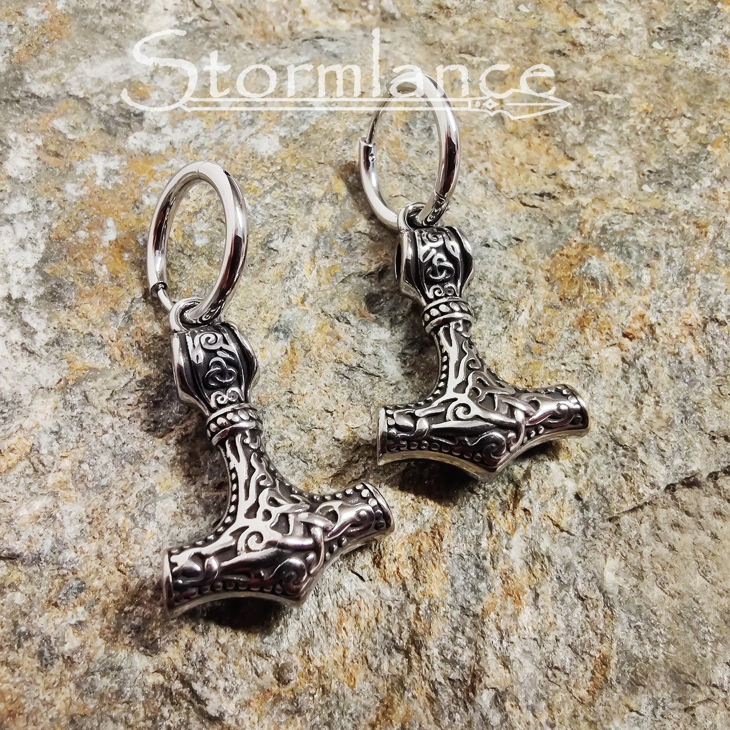 Mjolnir Earrings Silver in Color made of stainless steel laying on a stone slab