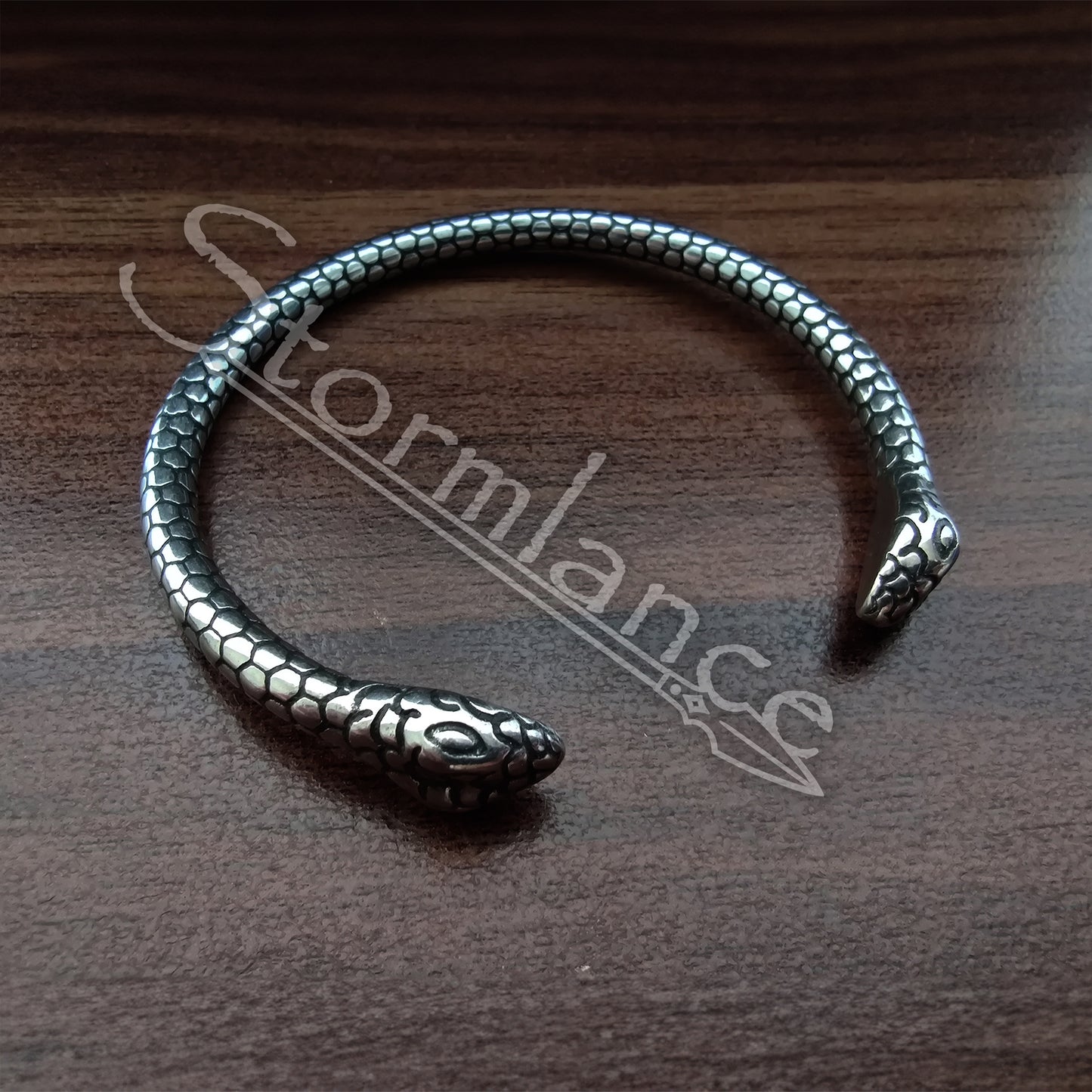 Snake Jormungandr Bracelet made of stainless steel laying on a wooden desk
