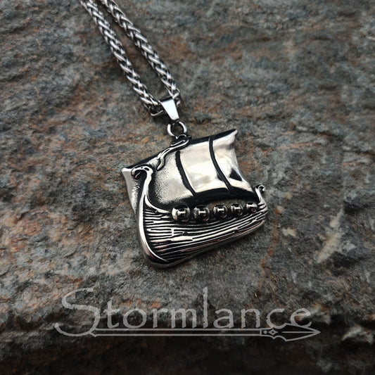 Viking drakkar ship pendant made of stainless steel, laying on a granite stone slab