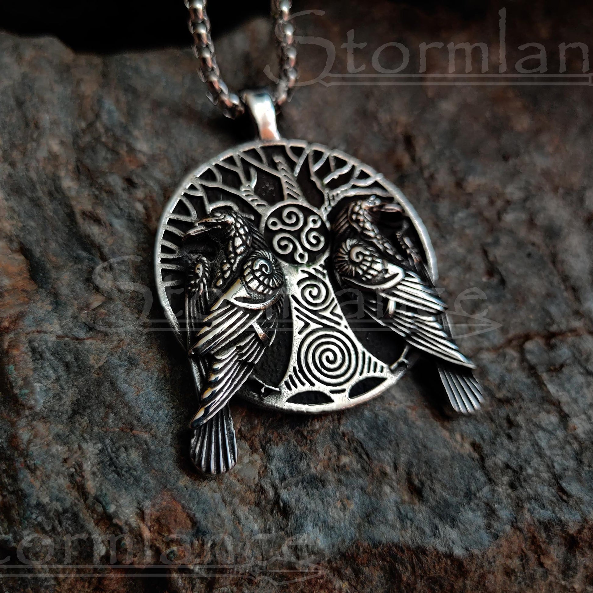 Yggdrasil (tree of life)pendant with huginn and muninn ravens  made of stainless steel, laying on a granite stone slab