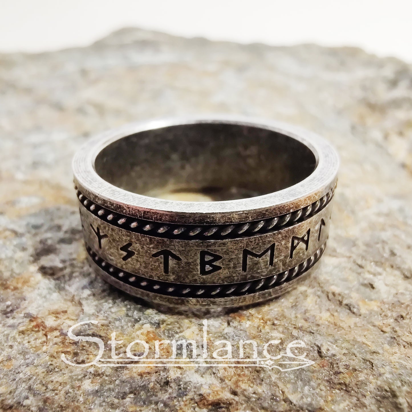 elder futhark rune ring made of stainless steel, laying on a granite stone slab
