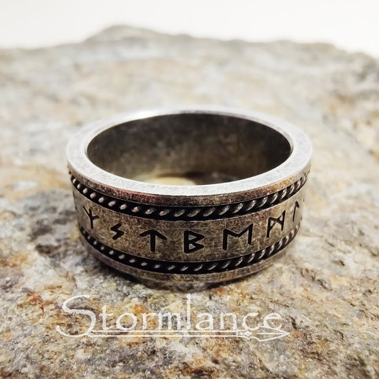 elder futhark rune ring made of stainless steel, laying on a granite stone slab
