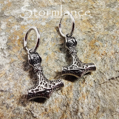 Mjolnir Earrings Silver in Color made of stainless steel laying on a stone slab