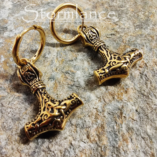 Mjolnir Earrings Gold in Color made of stainless steel laying on a stone slab