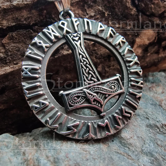 Mjolnir with elder futhark runes pendant made of stainless steel, laying on a granite stone slab