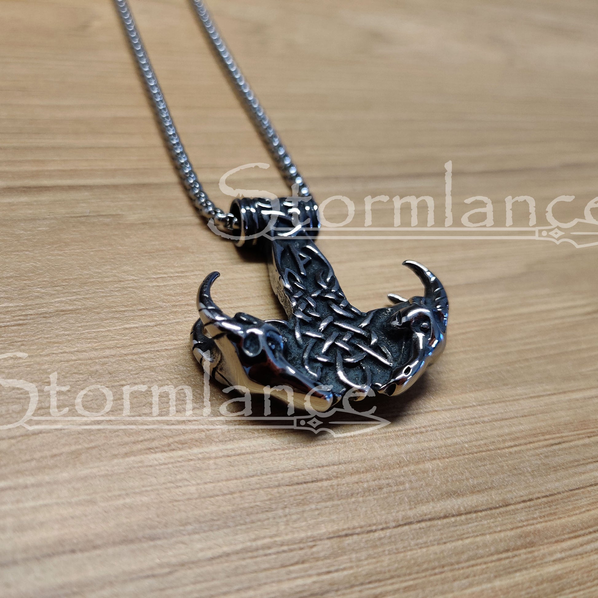Mjolnir with Thor's goats pendant made of stainless steel, laying on a wooden desk