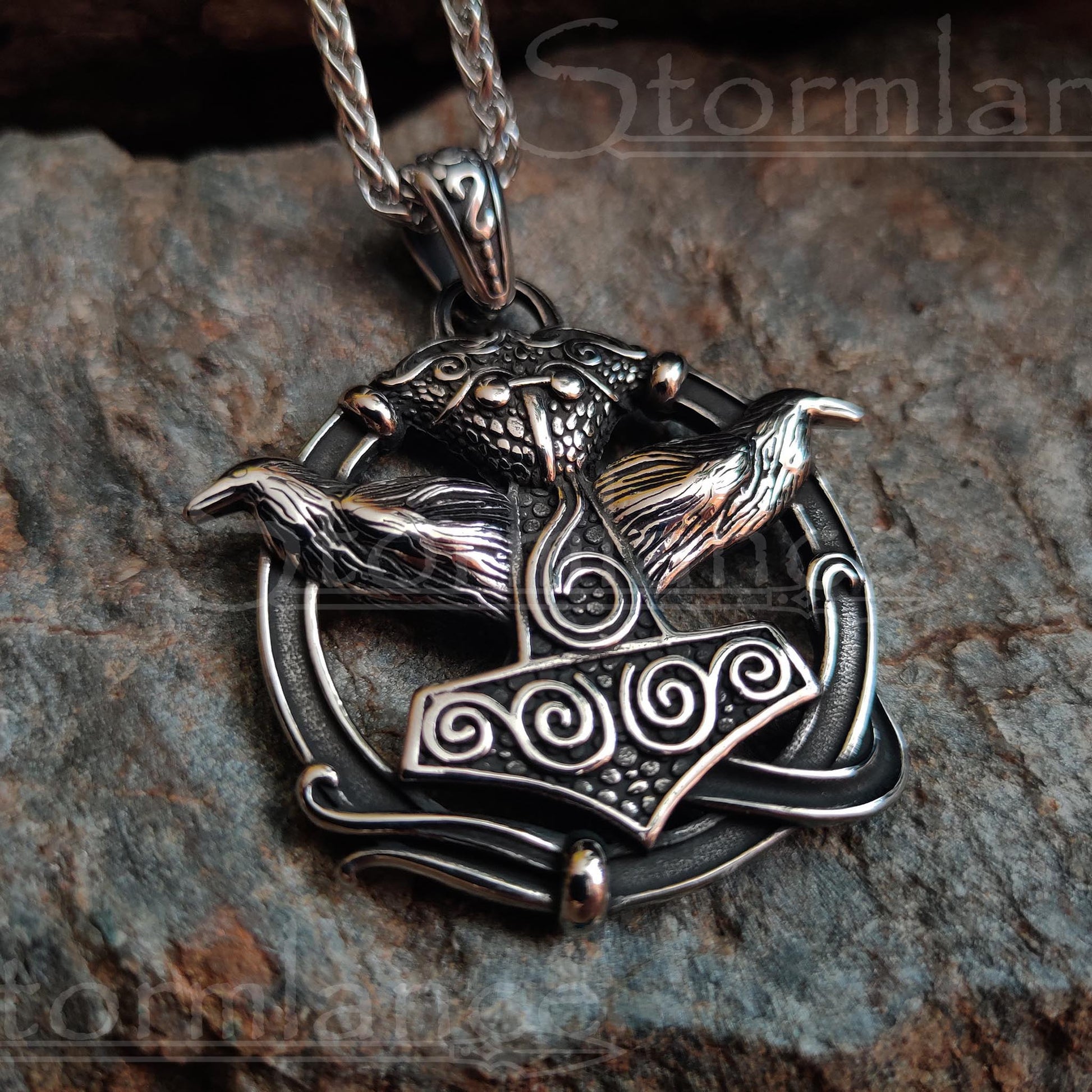 Mjolnir with huginn and muninn pendant made of stainless steel, laying on a granite stone slab