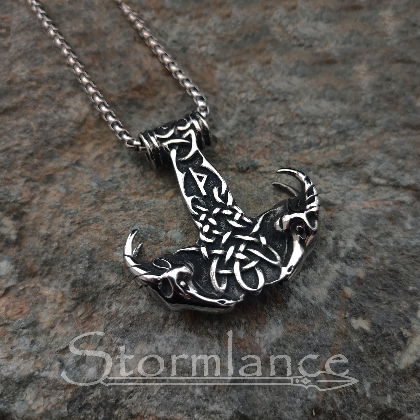 Mjolnir with Thor's goats pendant made of stainless steel, laying on a granite stone slab