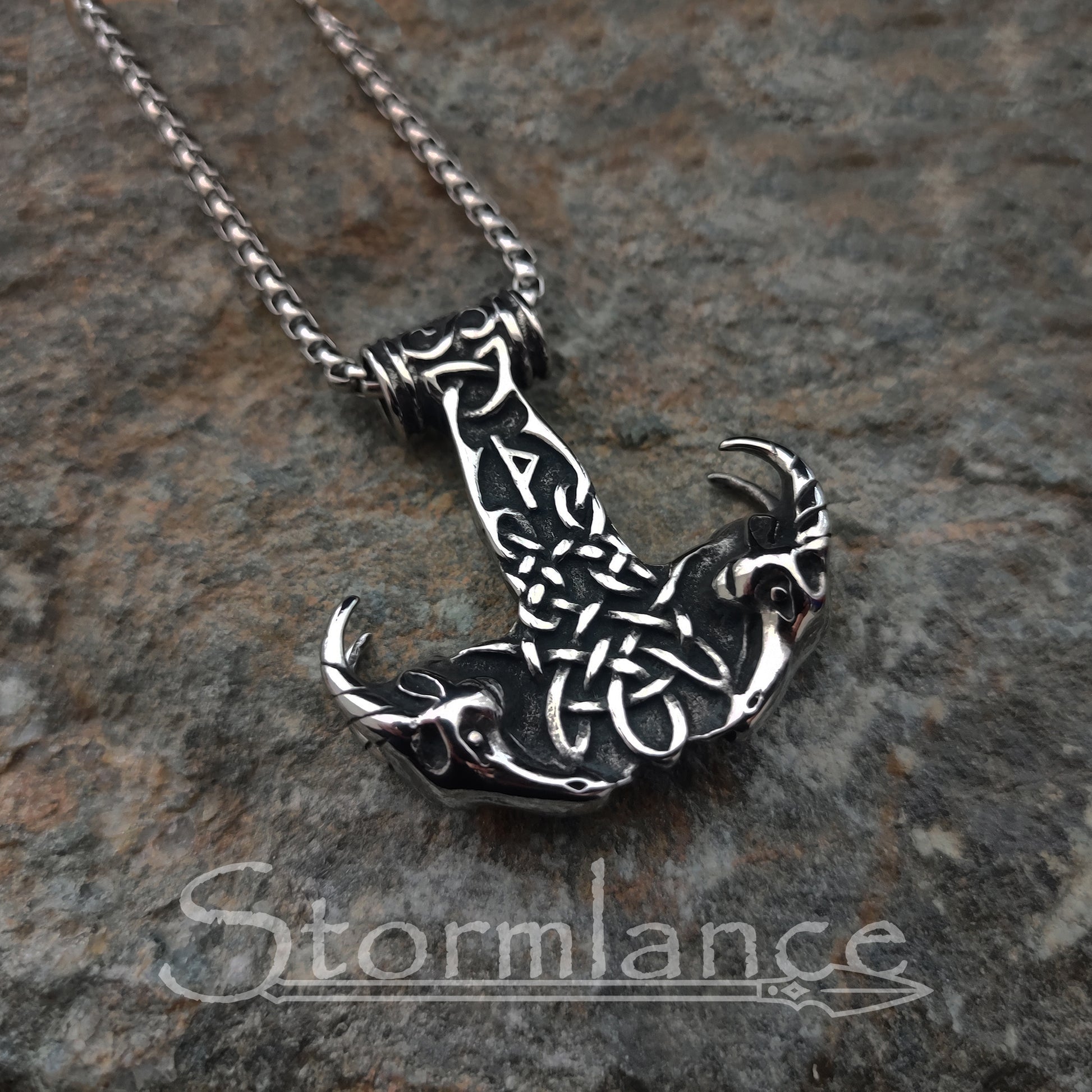 Mjolnir with Thor's goats pendant made of stainless steel, laying on a granite stone slab