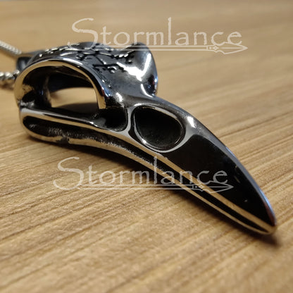 raven skull pendant with vegvisir made of stainless steel, laying on a wooden desk