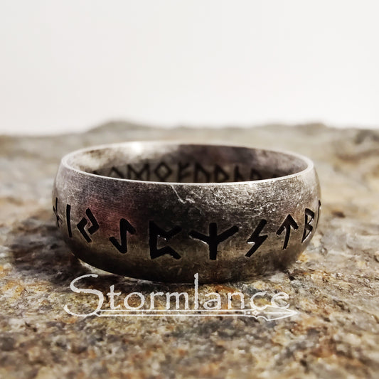 elder futhark runes ring made of stainless steel, laying on a granite stone slab