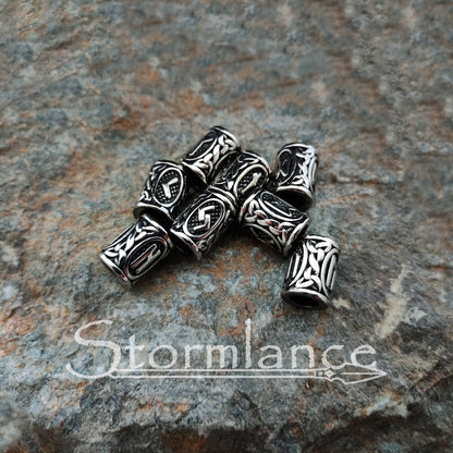 Viking Hair Rune Beads made of stainless steel laying on a granite rock slab