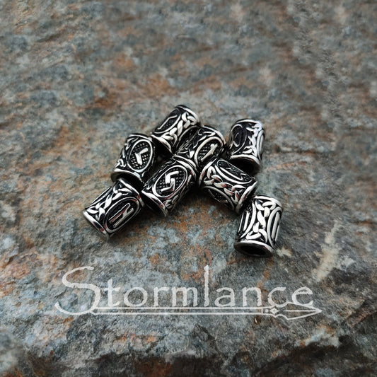 Viking Hair Rune Beads made of stainless steel laying on a granite rock slab