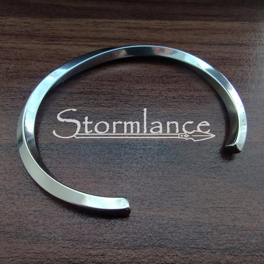 Shiny Twisted Simple Modern Arm Ring Made of Stainless Steel on a wooden background