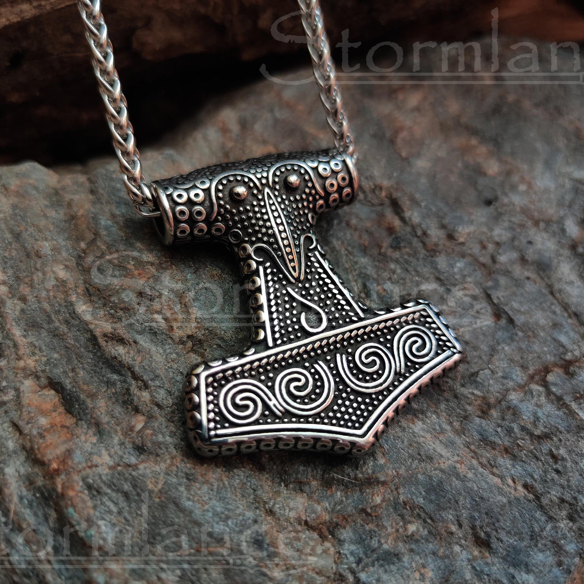 Skane mjolnir authentic replica pendant made of stainless steel, laying on a granite stone slab