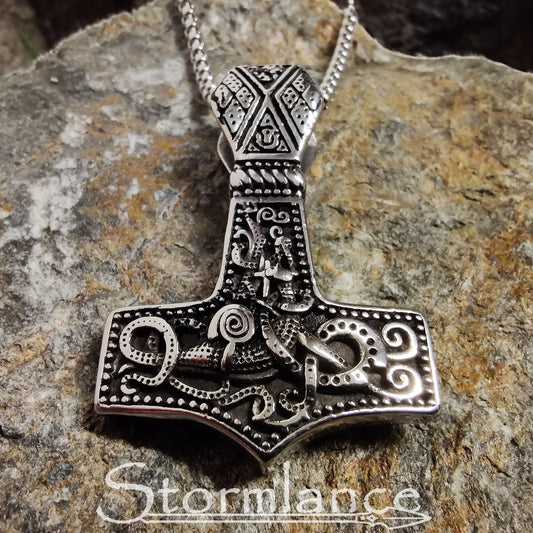 Scandinavian pattern Mjolnir pendant made of stainless steel, laying on a granite stone slab