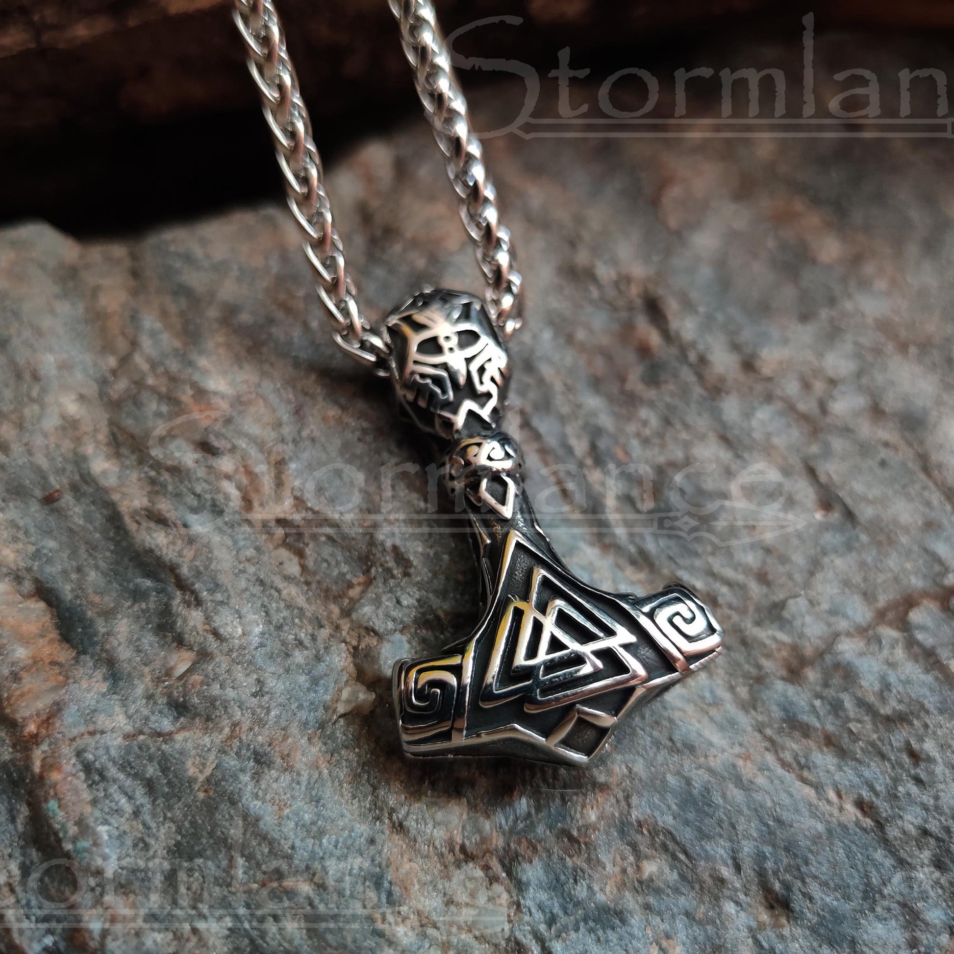 Valknut mjolnir pendant made of stainless steel, laying on a granite stone slab