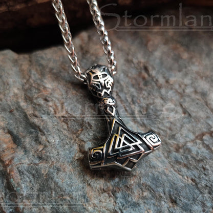 Valknut mjolnir pendant made of stainless steel, laying on a granite stone slab