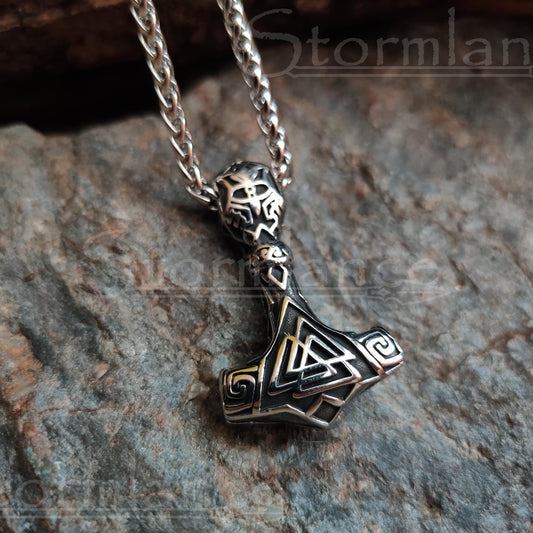 Valknut mjolnir pendant made of stainless steel, laying on a granite stone slab