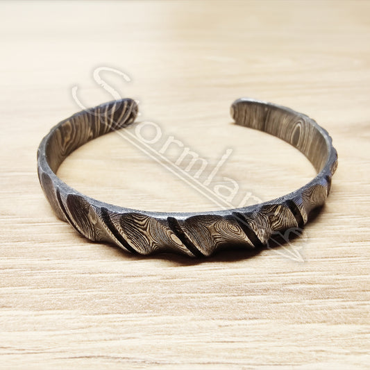 Twisted Cut Pattern Bracelet made of Damascus Steel laying on a wooden table