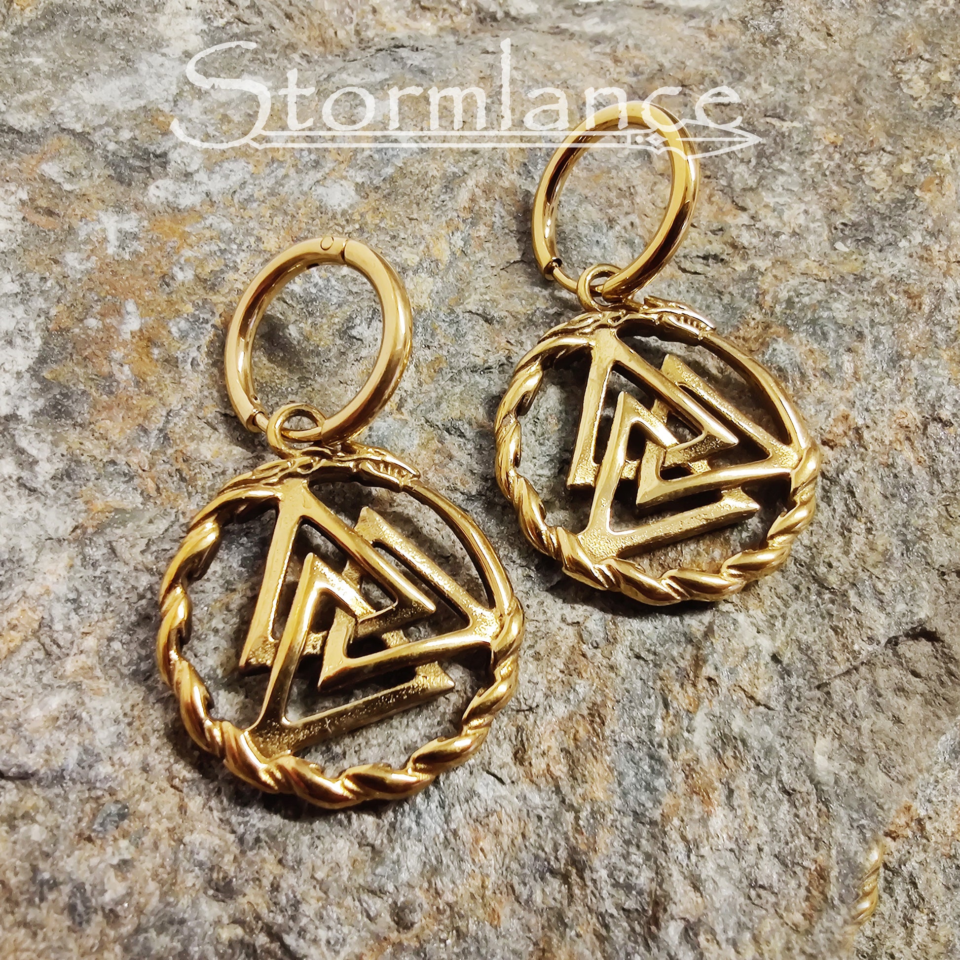 Valknut Earrings Gold in Color made of stainless steel laying on a stone slab