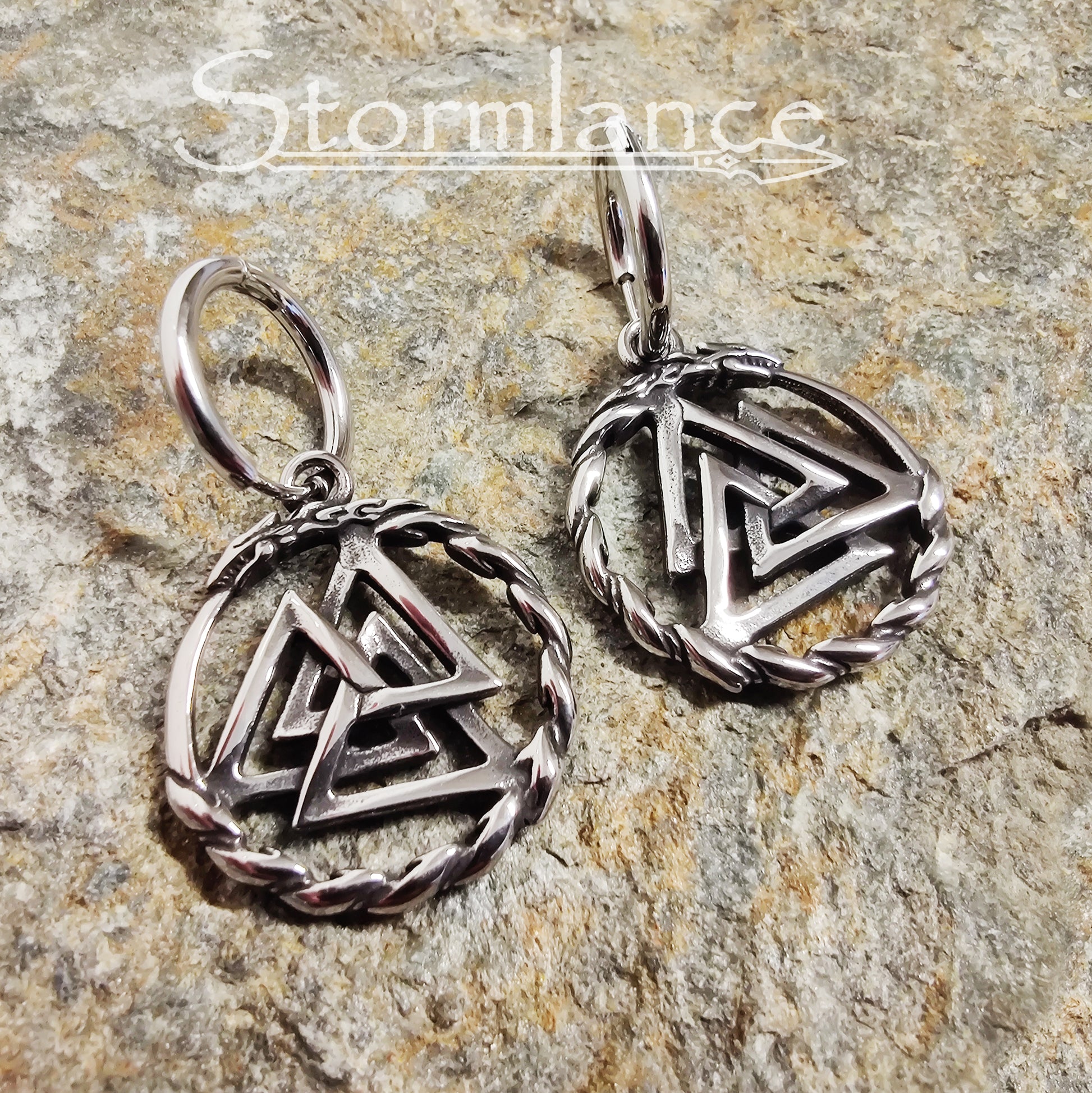 Mjolnir Earrings Silver in Color made of stainless steel laying on a stone slab