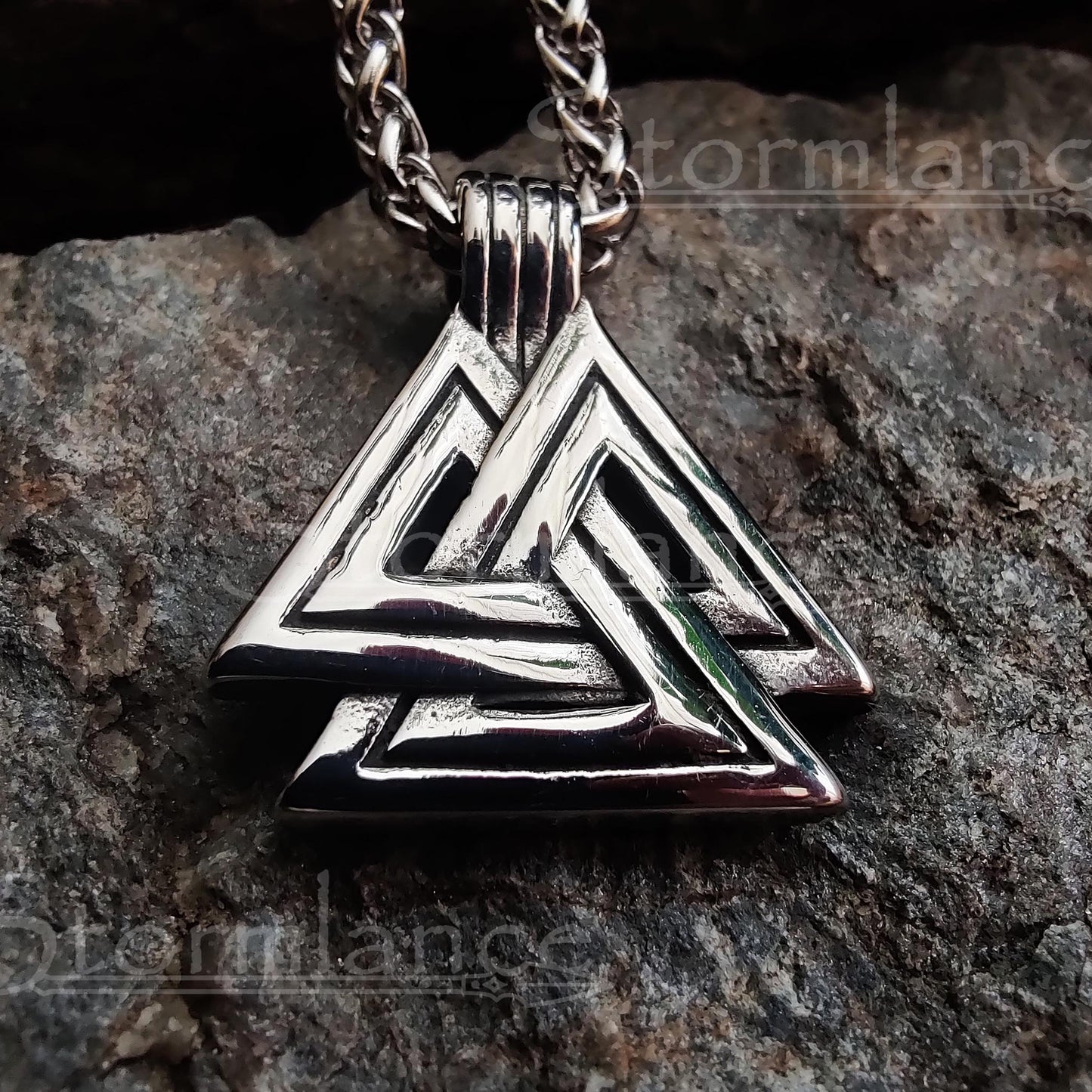 Valknut pendant made of stainless steel, laying on a granite stone slab