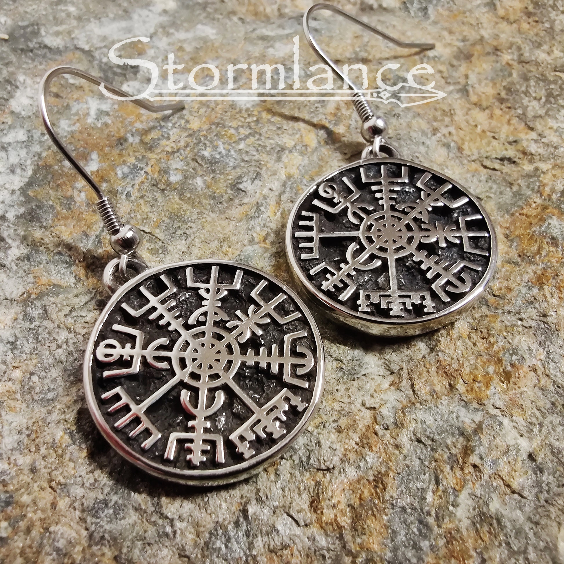 Vegvisir Earrings Silver in Color made of stainless steel laying on a stone slab