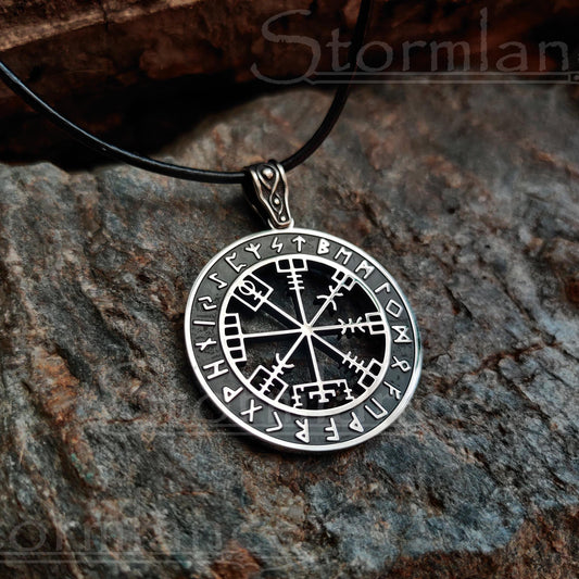 vegvisir with elder futhark runes pendant made of stainless steel, laying on a granite stone slab