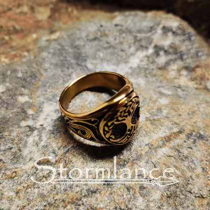 yggdrasil ring in gold color made of stainless steel, laying on a granite stone slab