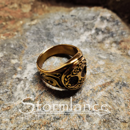 yggdrasil ring in gold color made of stainless steel, laying on a granite stone slab