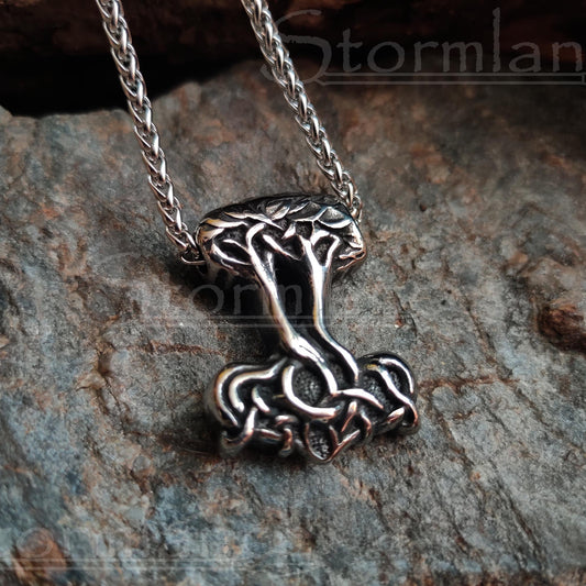 tree of life and thor's hammer in one pendant made of stainless steel, laying on a granite stone slab