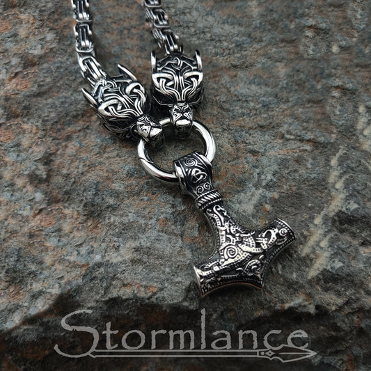 massive thor's hammer pendant with geri and freki wolves, made of stainless steel, laying on granite stone slab